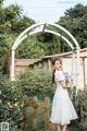 A woman in a white dress standing in a garden.