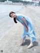 A woman in a blue dress standing on a beach.