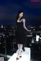 A woman in a black dress standing on a balcony.