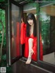 A woman in a red robe sitting on a window sill.