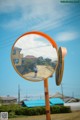 A person is reflected in a mirror on a pole.