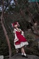 A woman in a red and white dress standing on a rock.