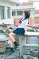 A woman in a school uniform sitting on a table.