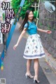 a woman in a blue shirt and white skirt is walking down the street